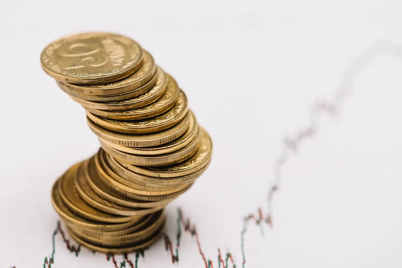 Stapel goldener Münzen über dem Börsendiagramm